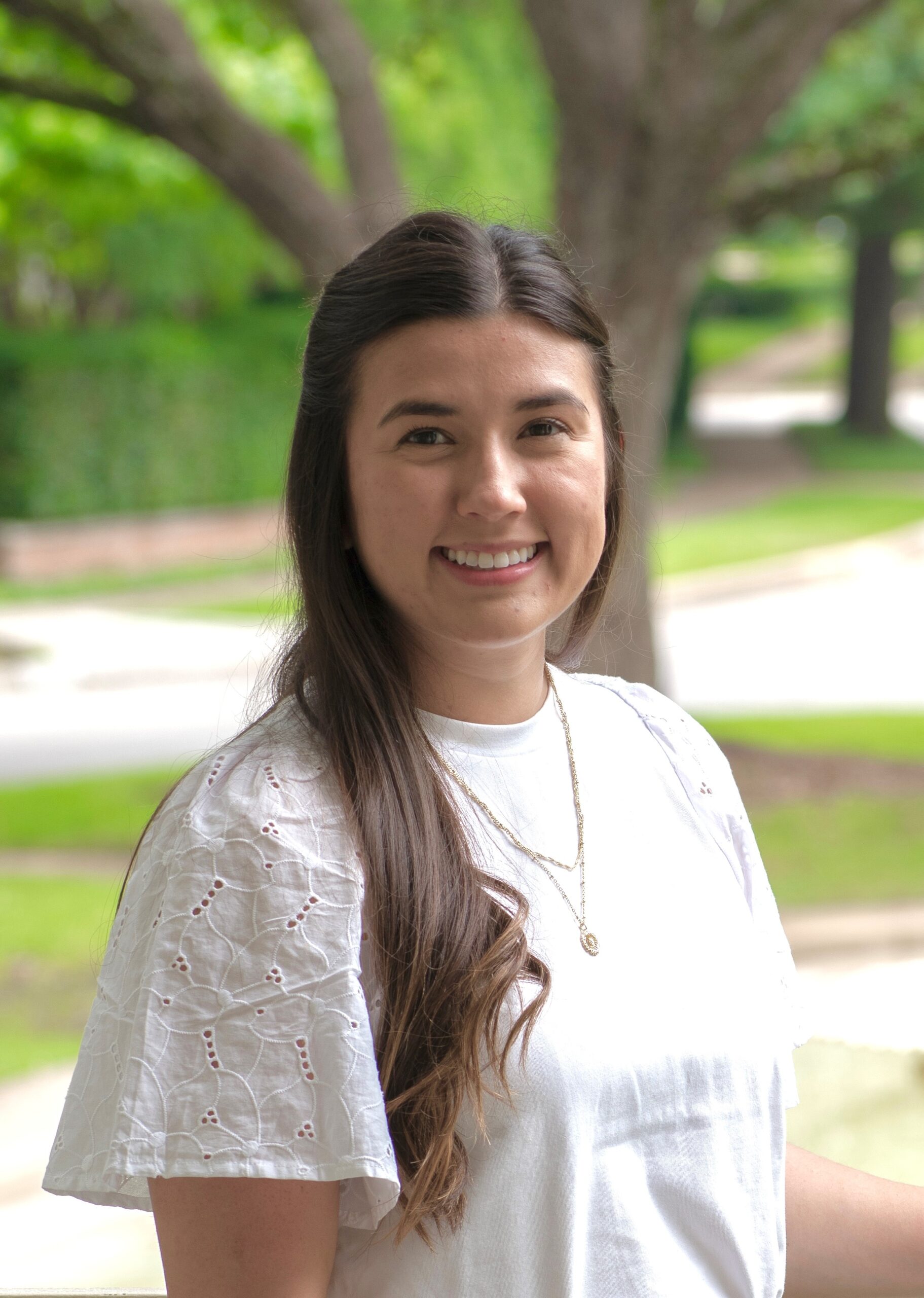 Smiling woman with long hair outdoors in natural light.