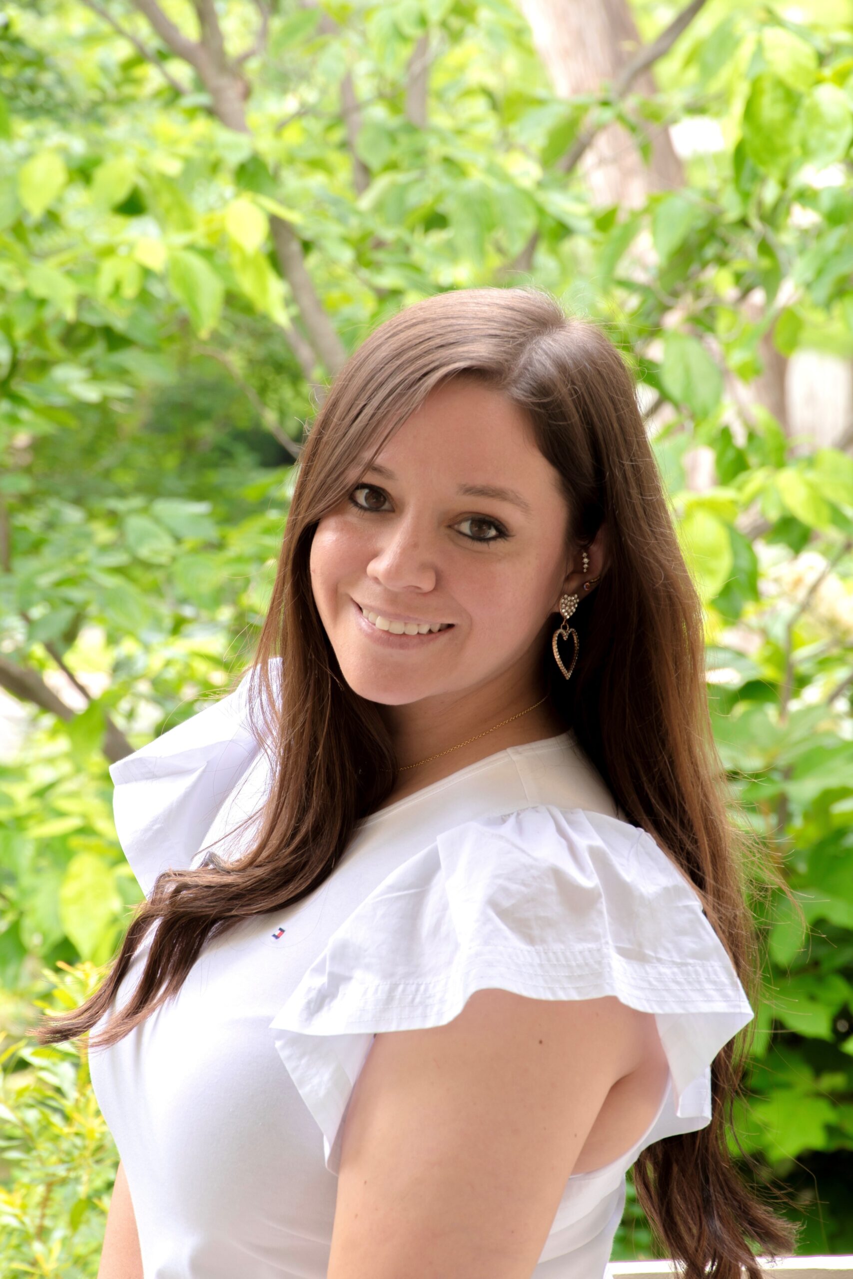 Smiling woman outdoors with soft natural lighting.